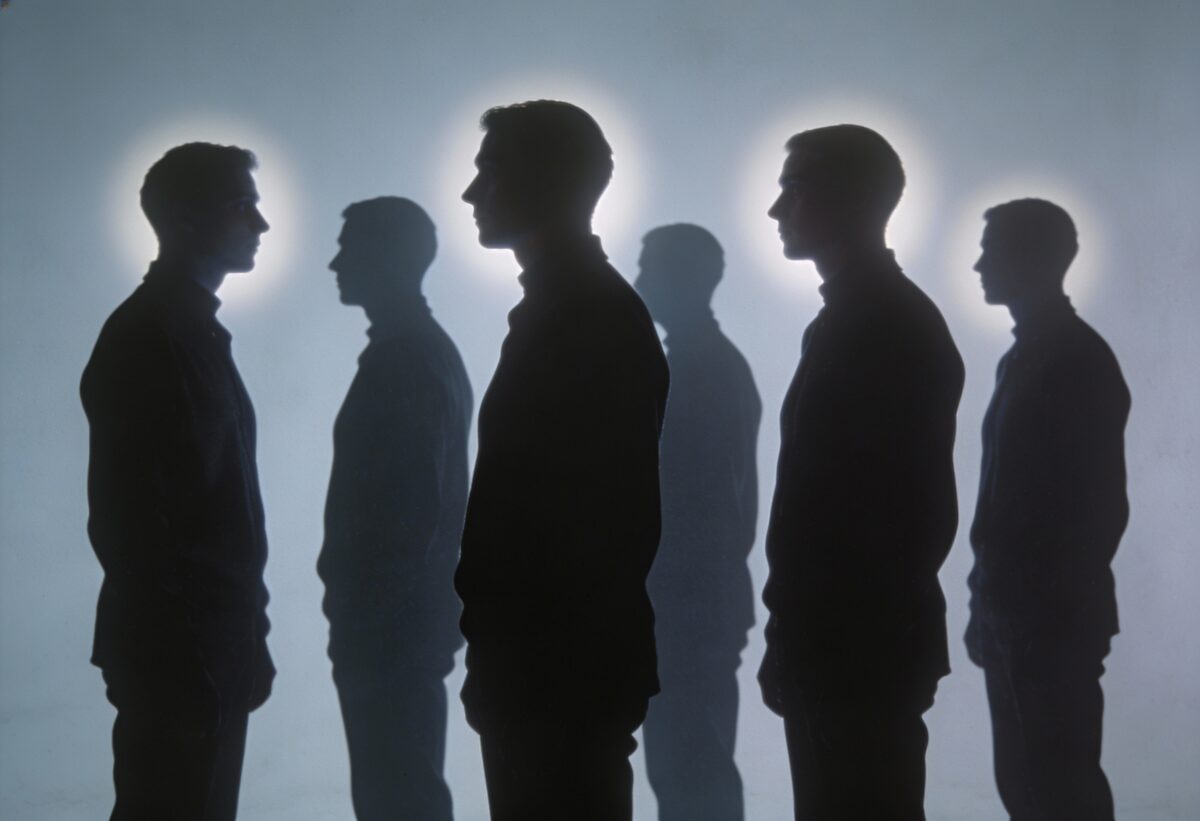 Siluet beberapa orang berdiri saling membelakangi dengan ekspresi yakin
